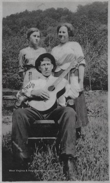 Goff pictured sitting while playing a guitar. His sister's, who's names are unknown, stand behind him.