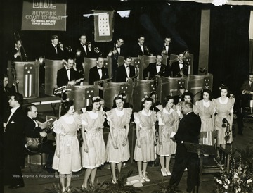 The Musical Steelmakers were the orchestra that performed on "It's Wheeling Steel" radio broadcast on NBC's Blue Network. Note the flag behind the performers on stage. The blue stars represented people who were serving in the war, and a gold star represented those who died in service.