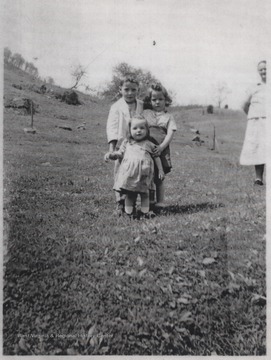 Murvel "Jack" Lilly, Juanita E. Lilly, and Nancy L. Lilly pose together for a picture. To the right, in the background, is their grandmother, Lula M. Cook. 
