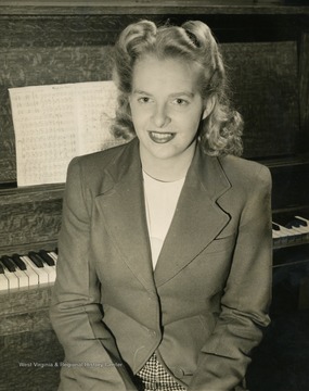 Caption accompanying photograph reads: "Shown seated at the piano during a rehearsal of the "Musical Steelmakers", heard Sundays on the Blue network at 5:30 pm, e.w.t., is Margaret June Evans, eldest member of the three Evans Sisters, vocal trio heard during each broadcast of the program. Miss Evans, whose father has worked for the sponsoring company as a steel roller for 29 years, was recently crowned "Miss West Va." by Carl C. Wayman, Commander of the nation's first American Legion Post, located in Wheeling."