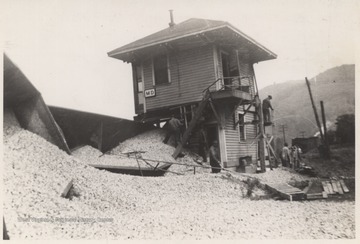 Nineteen Cars derailed, spilling it's contents at the M. D. Cabin.Pictured is engineer E. V. Rogers, conductor R. B. Tinsley, fireman E. W. Gwinn, and rear brakeman Carlos Garten examining the damage. 