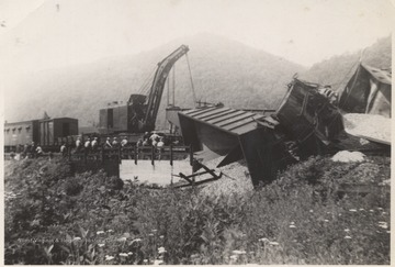 View of the damage when nineteen cars derailed. A crane is pictured in the background, perhaps prepared to lift the tipped cars.