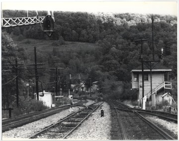 Eric Moody pictured walking across the tracks and advancing toward the railway cabin. Behind him, a sign reads, "Meadow Creek". 