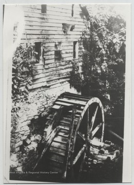 A water wheel is pictured beside a building.