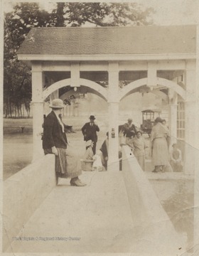 An unidentified group is pictured under and awning and on the edge of a bridge that hovers over the spring.