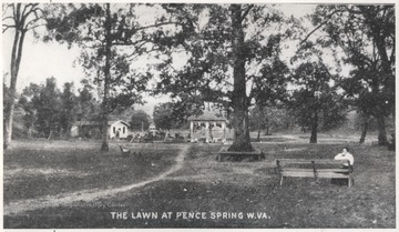 Photo from a postcard. A woman sits on a bench admiring the view on the right.