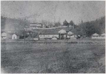 Jim Richmond home pictured on the upper left of the photograph. The large building in the center is W.m. Simmons Store. Small white building to the left is Dr. Lemon's office.