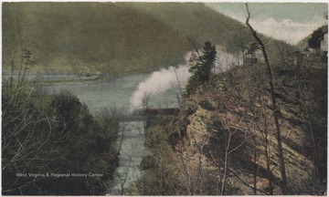 Steam billows from a train crossing over a creek beside a river.Published by J. A. Graham & Co.