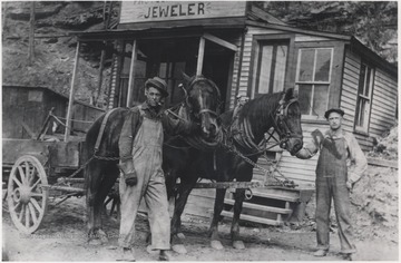 The two men are pictured outside of the store located in Happy Hollow with two horses pulling a wagon.
