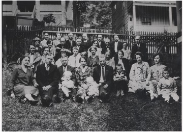 The family, who's members are unidentified, sit outside of their home and on the lawn.
