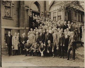 A group of men pose outside of the church building. Subjects unidentified.