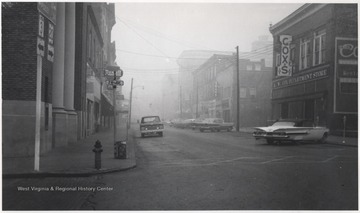 A car drives down the foggy street. 