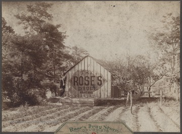A man poses by a painted shed that reads, "Truy Ropse's Drugs. Ask about Nyals."The photo description reads, "Sign No. 6. Located 5 miles above Hinton. Can be seen from County Road."