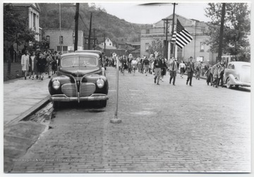 A marching band and parade spectators move past the courthouse and Memorial Building, pictured on the left of the photo.