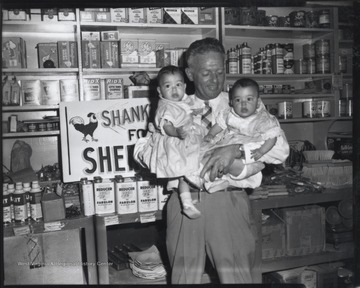 Shanklin holds two babies in front of a "Shanklin for Sheriff" campaign sign. His store was located on Second Avenue. 