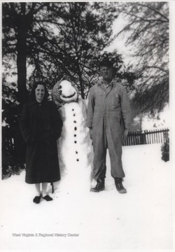 Glenna and Mark Shumate pose beside the snowman on the farm located near War Ridge. 