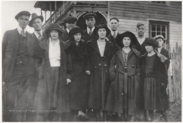 In the back row, from left to right, is Clyde Farley; Oren Meador; the rest are unidentified.In the front row, starting with the 3rd woman from the left is Sibyl Lilly; Clema Lilly (married Joe Hedrick). Next to the general store in the background is the True Post Office.