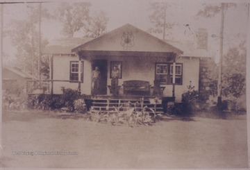 Two men stand outside on the porch of the C. C. C. camp building which is located near Pinecrest Sanitarium. Subjects unidentified.