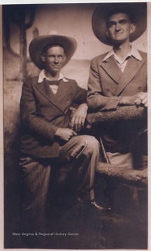 Wood (right) and an unidentified male companion pose in front of a "Wild West" scene with cowboy hats. 