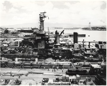 Men inspect the damage after the infamous Japanese attack. The "Wee Vee" as the ship was affectionately referred to, was raised from the bottom of Pearl Harbor where she was moored during the attack and towed to dry dock for repairs.
