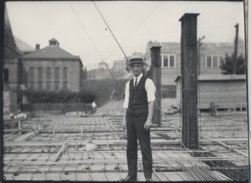 An unidentified and sharply dressed man stands at the site, perhaps supervising the progress. 