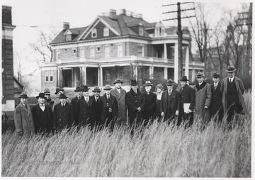 A group of unidentified men stand in a field that will become the Hall of Chemistry. In the background is the Purinton House.