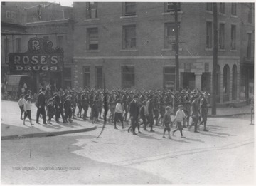 Children walk beside the troop as they pass Rose's Drug Store and the National Bank of Summers on Temple Street. Subjects unidentified. 