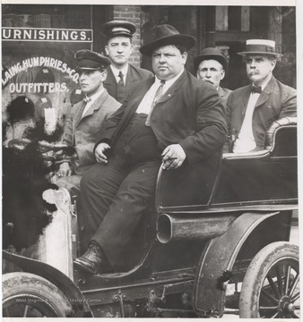 The first car ever purchased in the city was a two-cylinder Brush. John Lang, weighing 380 lbs., is pictured in the forefront. His associates are unidentified. 