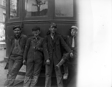 Four unidentified men in a trolley crew leading against a trolley car in Morgantown, W. Va.