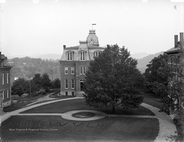 Image shows Woodburn Hall without the wings and displays "WVU" dug into the grass in Woodburn Circle.