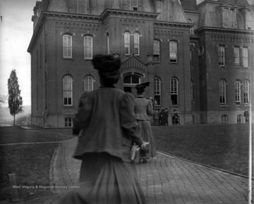 The image shows the back of a female student rushing into Woodburn Hall.