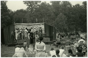 Performance of EcoTheater Company at Sandell Farm in Union, W. Va.  The stage used by EcoTheater was made from a farm wagon that was transformed into a mobile stage and that could be ready for a performance quickly.  EcoTheater performed at a number of outdoor venues such as state parks.Maryat Lee (born Mary Attaway Lee; May 26, 1923 – September 18, 1989) was an American playwright and theatre director who made important contributions to post-World War II avant-garde theatre.  She pioneered street theatre in Harlem, and later founded EcoTheater in West Virginia, a community based theater project.Early in her career, Lee wrote and produced plays in New York City, including the street play “DOPE!”  While in New York she also formed the Soul and Latin Theater (SALT), and wrote plays centered around the lives of the actors in the group.In 1970 Lee moved to West Virginia and formed the community theater group EcoTheater in 1975.  Beginning with local teenagers from the Governor’s Summer Youth Program, the rural theater group grew, and produced plays based on oral histories collected from the local community.  Each performance of an EcoTheater play involved audience participation and discussion.  With the assistance of the Humanities Foundation of West Virginia, guest scholars became a part of EcoTheater.