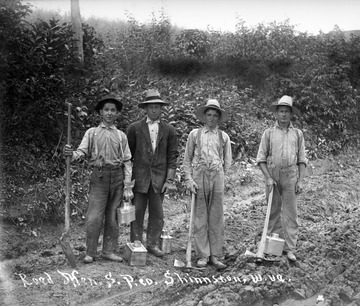 Unidentified men pose for a portrait while working on a road.