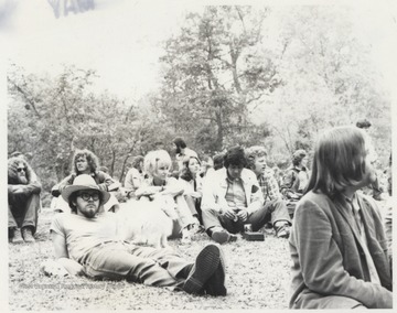 A group including Connie and Leo Chabot lounge on a grass lawn. This photograph is from a series of photos from Appalachian Folk Music Festivals, including the Ivydale and John Henry festivals. 