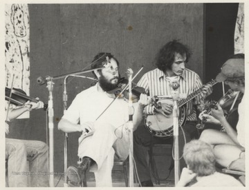 Franklin George and George Ward perform seated on a stage. This photograph comes from a series of photos from Appalachian Folk Music Festivals, including the Ivydale and John Henry festivals. 