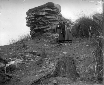 Two women and a man are pictured beside the rock formation, formally known as Dorsey's Knob. Subjects unidentified. 