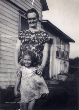 "Granny Hill" holding Mary Sirk, while posing outside a house.