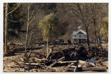 Damaged trees and debris surround a house after the flood.  The damage occurred during the November 1985 flood in the area around Parsons, Elkins, Onego, and Mounth of Seneca, W. Va.