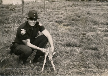 Bill Sirk in uniform, holding a very young fawn.