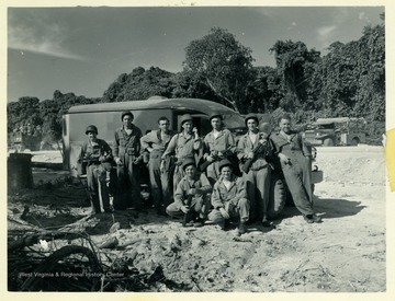 Marshall L. Williamson and the 57th Naval Construction Battalion with their ambulance. "This is our ambulance. The first and third fellows in the back are [corpsmen]. The fellow from the right side, who is squatting down is a [corpman] also. What do you think of the road? We built it."