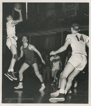 West, who is mid-air and ready to shoot the ball, played for East Bank High School as the team's starting small forward. He was named All-State from 1954–56, then All-American in 1956 when he was West Virginia Player of the Year, becoming the state's first high-school player to score more than 900 points in a season. 