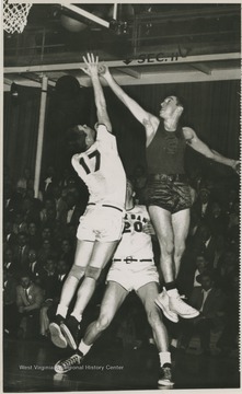 East Bank High School's Gary Stover, No. 17, and Morgantown's Jay Jacobs, No. 3, jump for a rebound during the championship game. Jerry West, not pictured, was also playing at this game as the team's starting small forward.West led East Bank High School to victory at this game, scoring 43 of the 71 points against Morgantown. The final score was 71-56. It was the first time East Bank High School won the state championship title.
