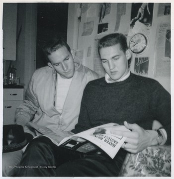 Akers, left, reads over West's shoulder as the two look at a magazine article together. 