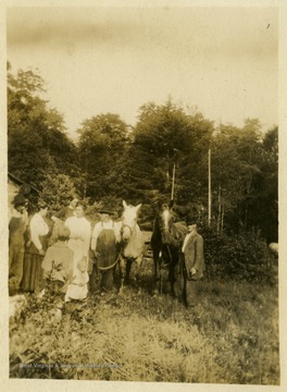 The man to the far left is Bob Cooper. A young Ben Thompson is pictured in the forefront with his back to the camera. To the left of the horses is Frank Cooper, and to the right of the horses is Jeff Roby. The women are unidentified.This image is part of the Thompson Family of Canaan Valley Collection. The Thompson family played a large role in the timber industry of Tucker County during the 1800s, and later prospered in the region as farmers, business owners, and prominent members of the Canaan Valley community.Ben Thompson was the son of George Thompson. He became a well known farmer in Canaan Valley. 