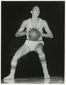 Jerry West appears to be preparing to either make a basket or pass the ball to a teammate in this image.