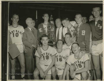 Jerry West, pictured holding the trophy, poses with his East Bank High School basketball team after winning the state championship. West led his team as the starting small forward. He was named All-State from 1953–56, then All-American in 1956 when he was West Virginia Player of the Year, becoming the state's first high-school player to score more than 900 points in a season.West was born in Cheylan, W. Va. in 1938. After high school, he went on to play basketball for West Virginia University and then rose to fame as a player for the Los Angeles Lakers of the NBA before becoming a basketball coach and manager. 
