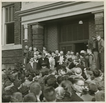 A crowd celebrates the victory in front of East Bank High School.Jerry West led the East Bank High School basketball team to its first ever West Virginia state championship title. He was named All-State from 1953–56, then All-American in 1956 when he was West Virginia Player of the Year, becoming the state's first high-school player to score more than 900 points in a season.West was born in Cheylan, W. Va. in 1938. After high school, he went on to play basketball for West Virginia University and then rose to fame as a player for the Los Angeles Lakers of the NBA before becoming a basketball coach and manager. 