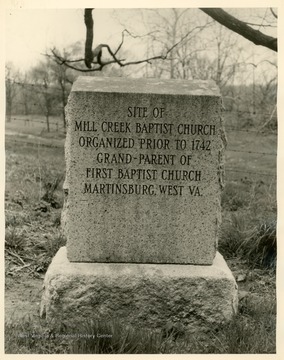A caption on the reverse side of the image reads: "Marker at site of Mill Creek Baptist Church; erected in 1958 by First Baptist Church, Martinsburg."The Mill Creek Baptist Church building does not stand here any longer.  The stone marker was placed in 1958.