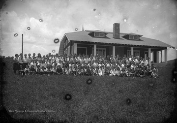 The girls camp poses outside of a building for a group photo. Subjects unidentified. 