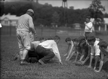 A man identified as "Rogers" joins the boys in a game of football. The boys are unidentified. 